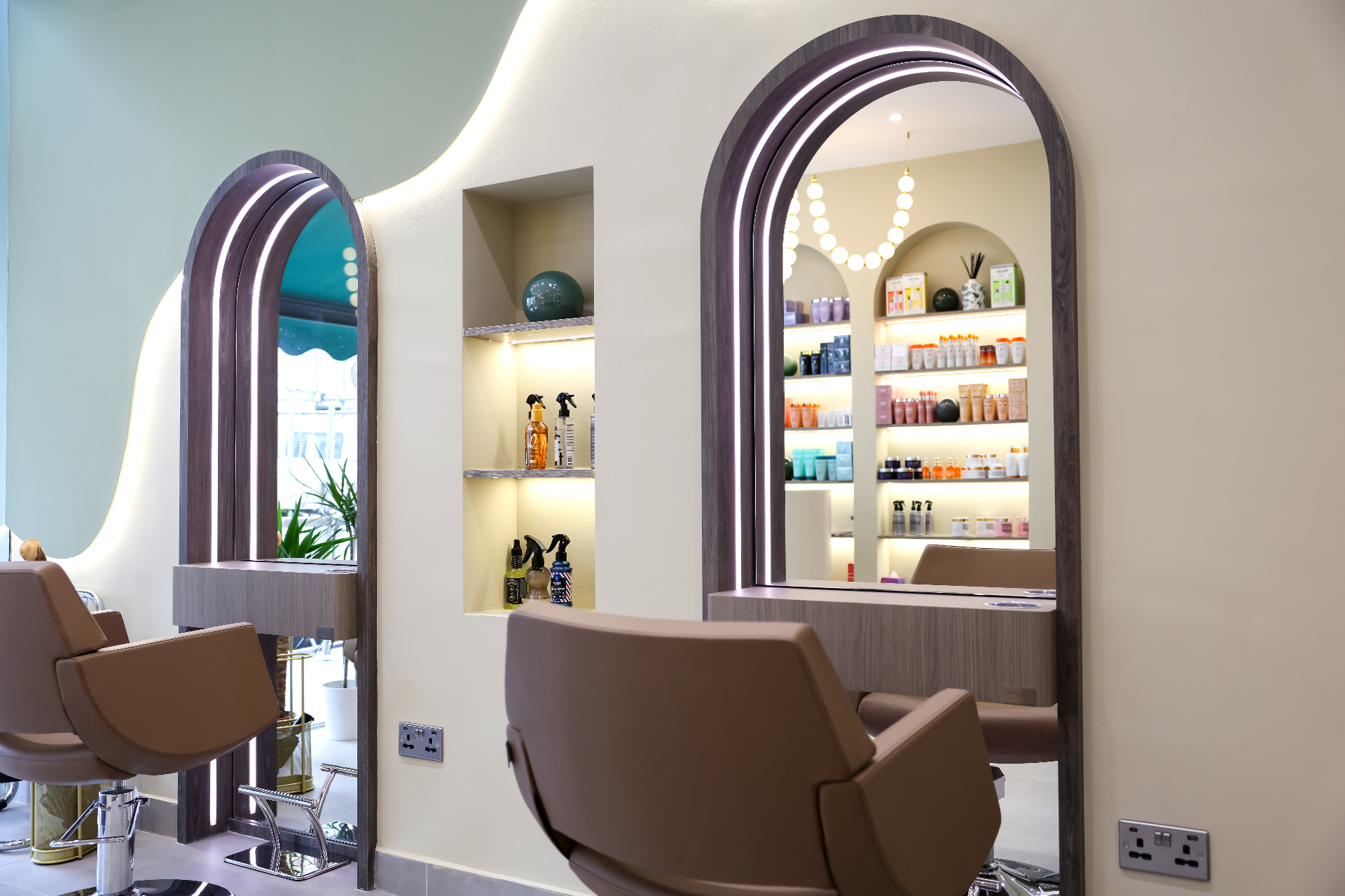 Marnis styling area , arched mirrors with backlit halos, sculpted sage wall and warm walnut detail